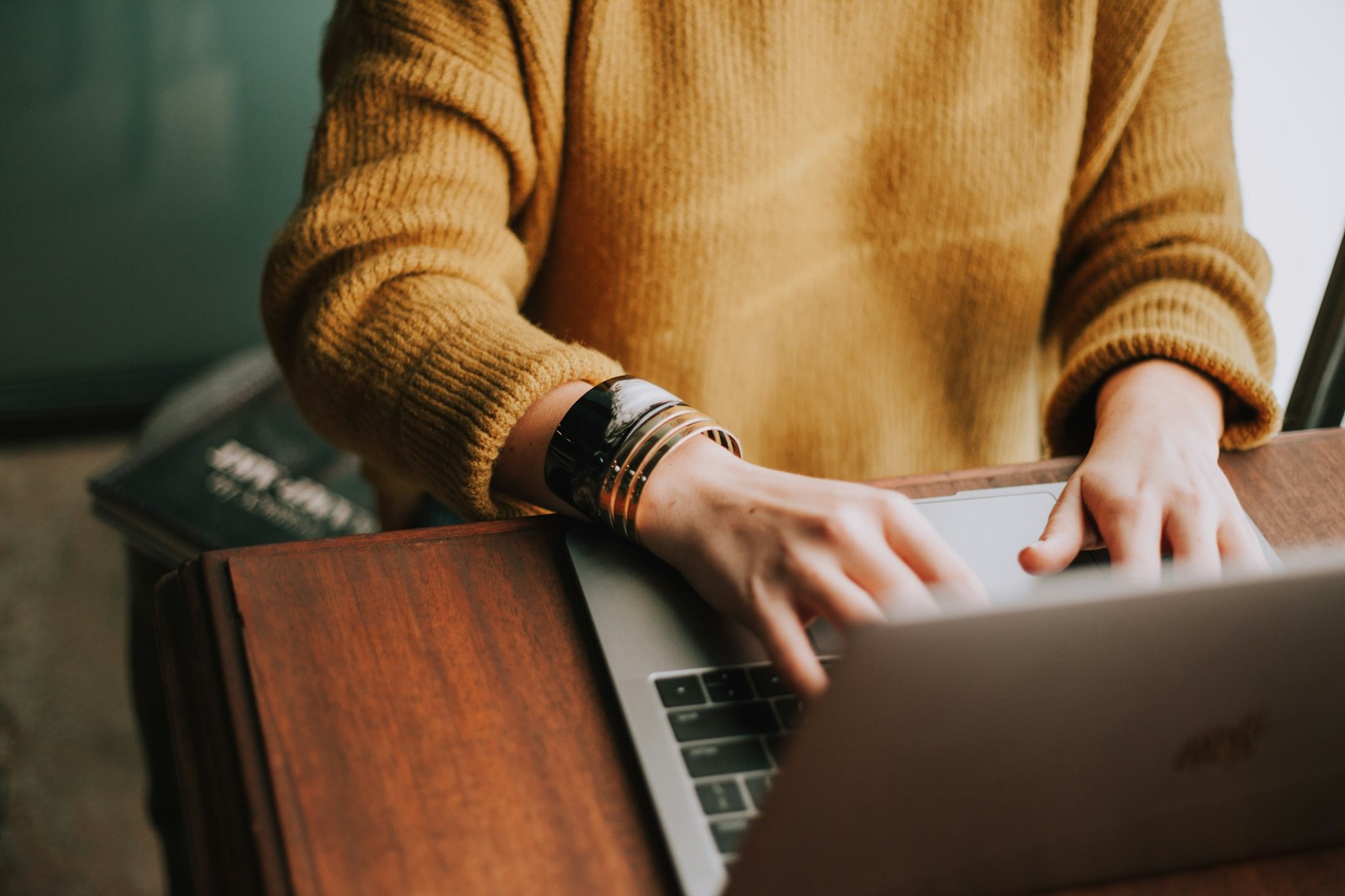 Woman in glasses opening a cardboard box while looking at a laptop, processing her online order and feeling disappointed with the delivery in her home office